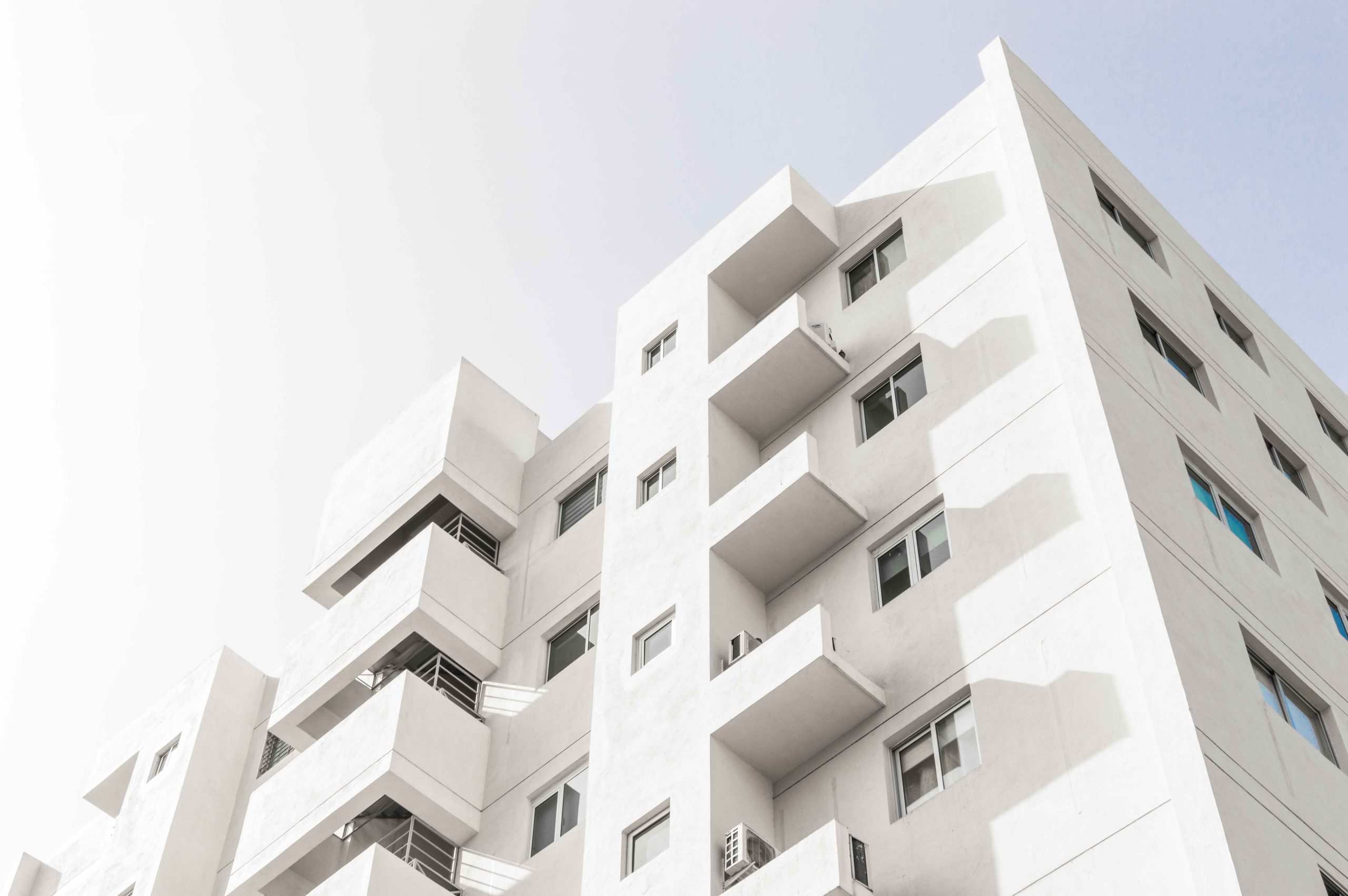 disparo-de-angulo-bajo-de-la-fachada-de-un-edificio-moderno-blanco-bajo-un-cielo-azul-claro_11zon